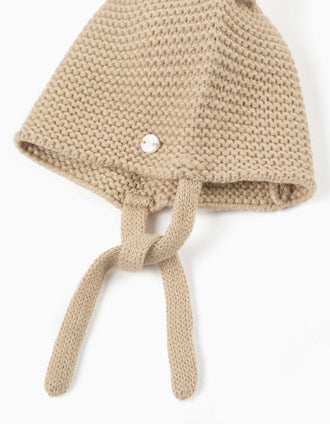 Gorro de punto con pompones y tirantes para recién nacidos, beige/blanco